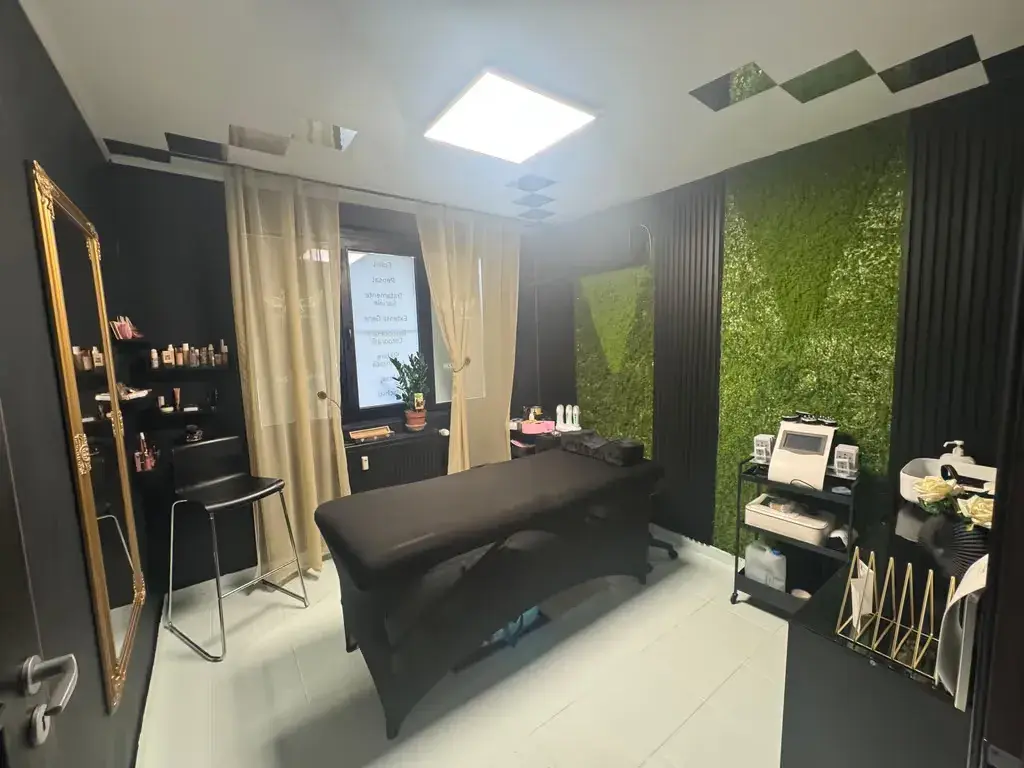 Interiorul salonului Angel's Beauty, cu masă de masaj și perete verde decorativ